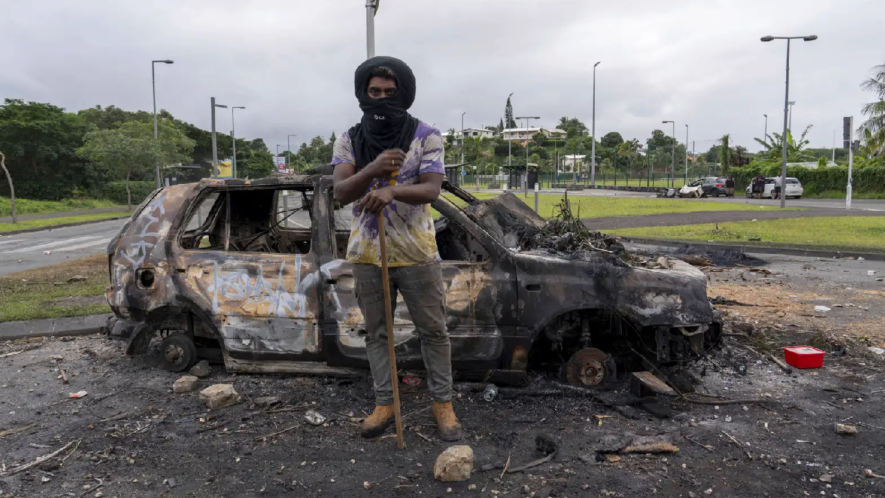 A Katan protesting in New Caledonia, a vehicle turned to ashes